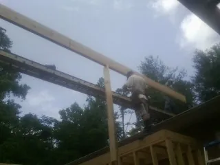 Carpenter setting a ridge beam over a new addition frame — Ice Dam Removal by Roofing Brothers in Radford