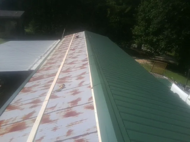 Old rusted panels beside newly installed green metal roofing — Wind Damage Roof Repair by Roofing Brothers in Radford