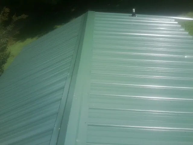 New green metal panels meeting at the ridge of a roof — Flat Roof Repair work by our crew in Radford
