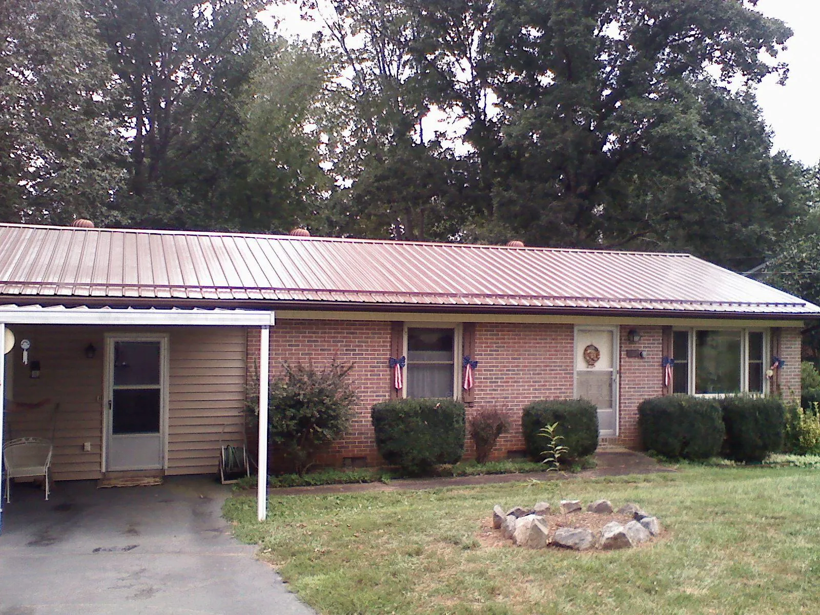 Bronze metal roof and carport on a brick ranch home — Roof Repair work by our crew in Radford