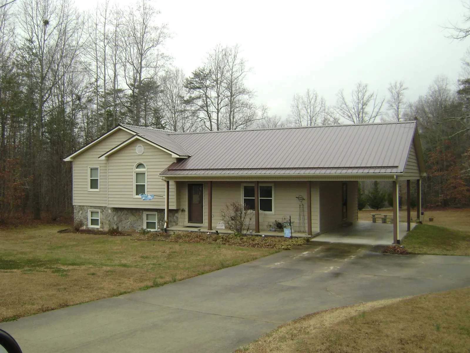 Brown metal roof on a tan split level home with an attached carport in Radford
