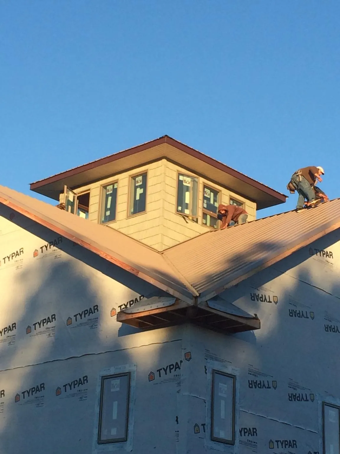 Roofers working around a rooftop cupola on a new metal roof at sunset — Roof Waterproofing in Radford by Roofing Brothers